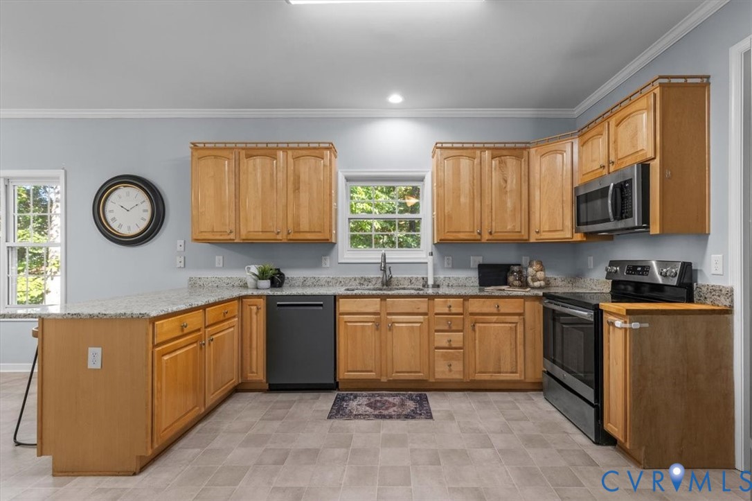 Kitchen featuring natural wood cabinetry, Granite countertops, stainless steel appliances, and vinyl flooring