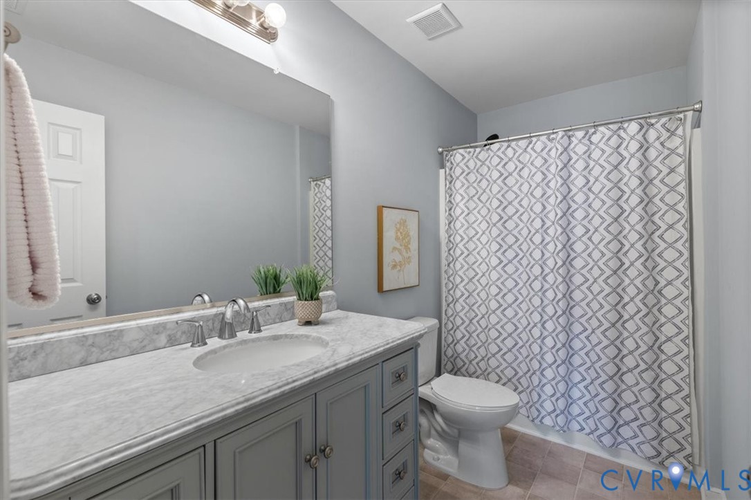 Hall bath featuring large vanity with stone countertop, and tub/shower enclosure