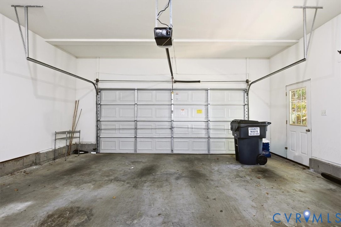 Multi-car garage featuring a sectional overhead door, automated garage door opener, concrete flooring, and an exterior access door with an inset window
