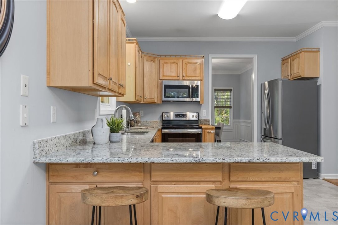 Kitchen featuring natural wood cabinetry, Granite countertops, stainless steel appliances, and vinyl flooring