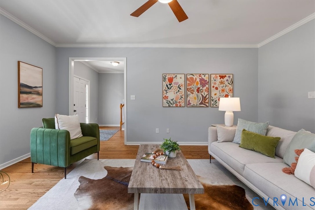 Living area featuring wood flooring, a fireplace, crown molding, and ceiling fan