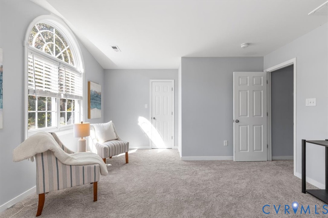 Primary bedroom featuring ensuite, new carpeting, ceiling fan, sitting area, and huge walk in closet