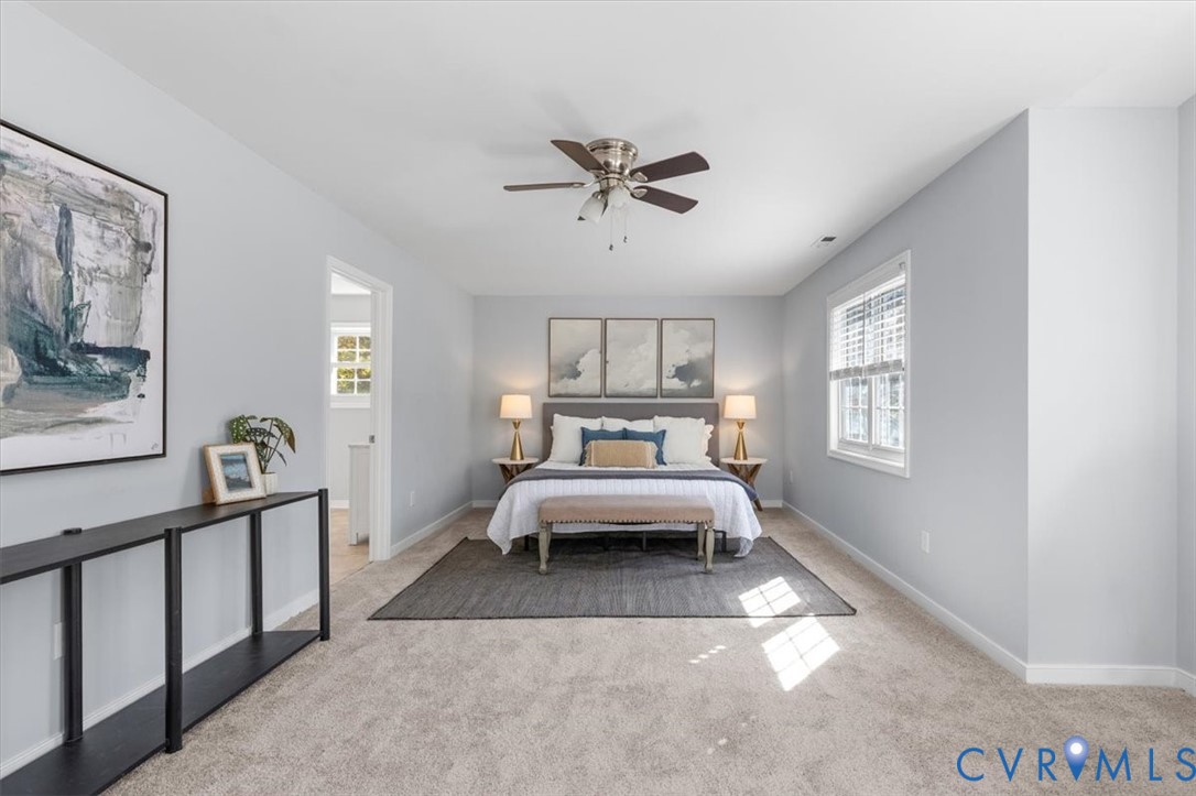 Primary bedroom featuring ensuite, new carpeting, ceiling fan, sitting area, and huge walk in closet