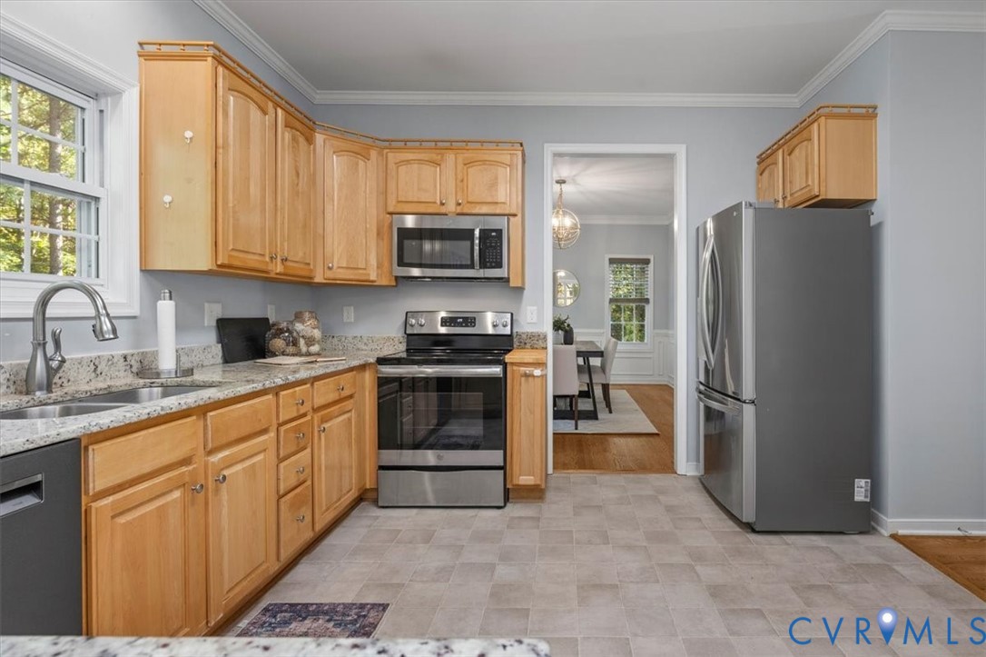 Kitchen featuring natural wood cabinetry, Granite countertops, stainless steel appliances, and vinyl flooring