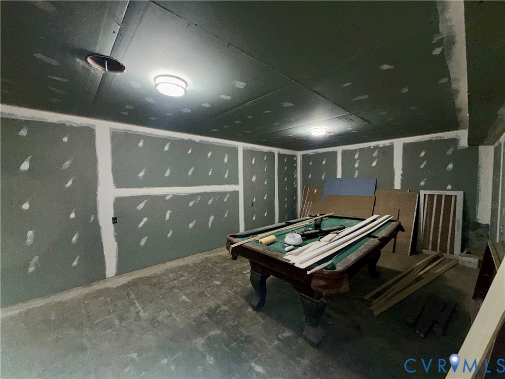 Interior space featuring unfinished drywall wall panels and ceiling panels with flush-mounted circular lighting