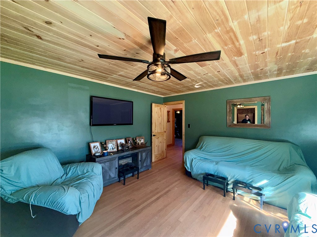 Natural wood-plank ceiling, wood-finish flooring, and a central ceiling fan with integrated lighting
