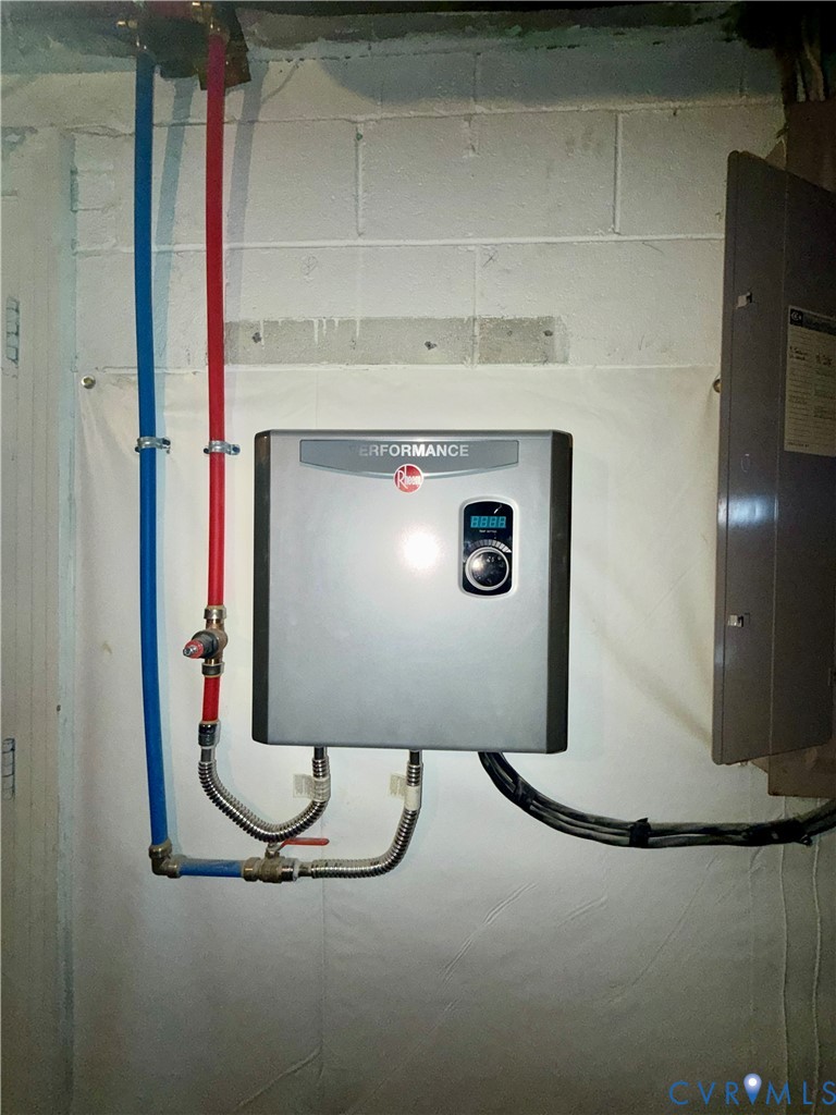Wall-mounted tankless electric water heater featuring a digital control interface and flexible supply lines