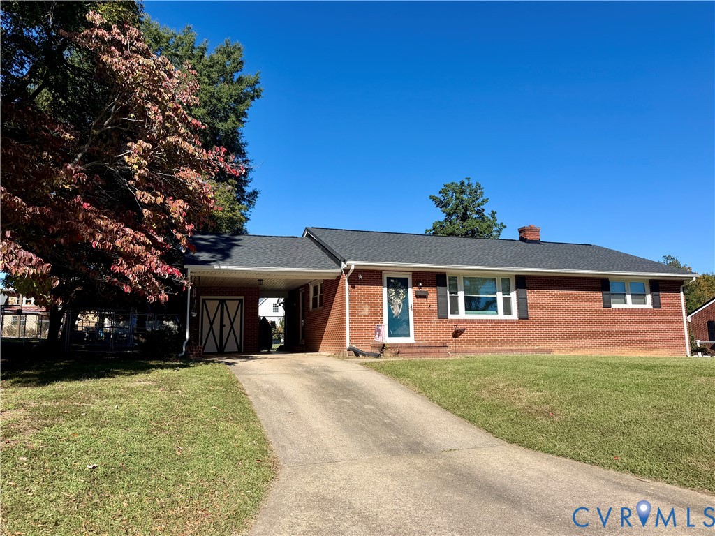 Single-story brick exterior featuring a shingled roof, attached carport with storage, and mature landscaping