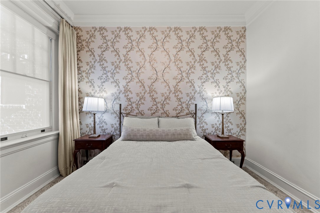 Bedroom featuring patterned wallpaper, crown molding, and sash windows