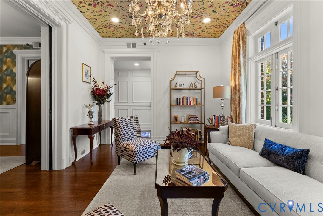 Interior space featuring patterned ceiling treatment, crystal chandelier, wood-finish flooring, multi-pane windows with grid detailing, and extensive wall molding