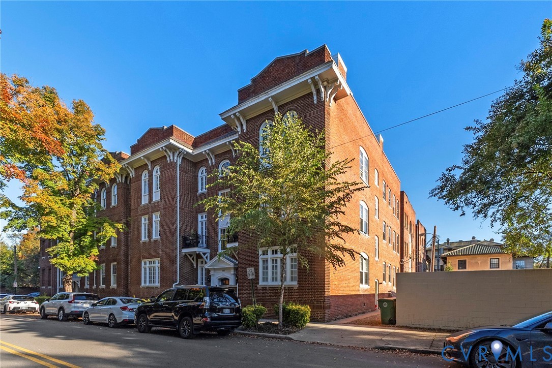 Multi-story brick exterior featuring ornate corbelled cornices, arched window detailing, wrought iron balconies, and a decorative roofline parapet