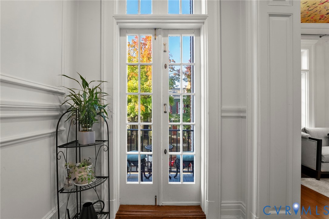 French doors featuring divided-lite glass panes, transom window, detailed wall wainscoting, and wood flooring