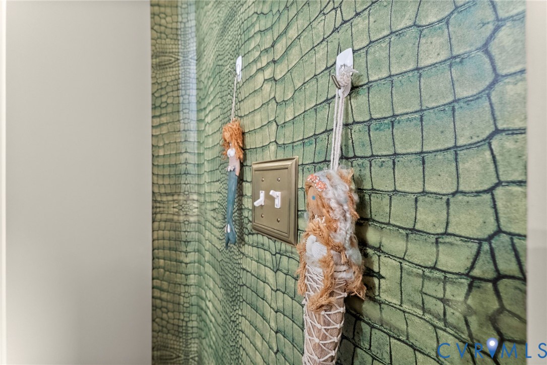 Textured green alligator-patterned wallpaper accented by a metallic-finish double toggle light switch plate