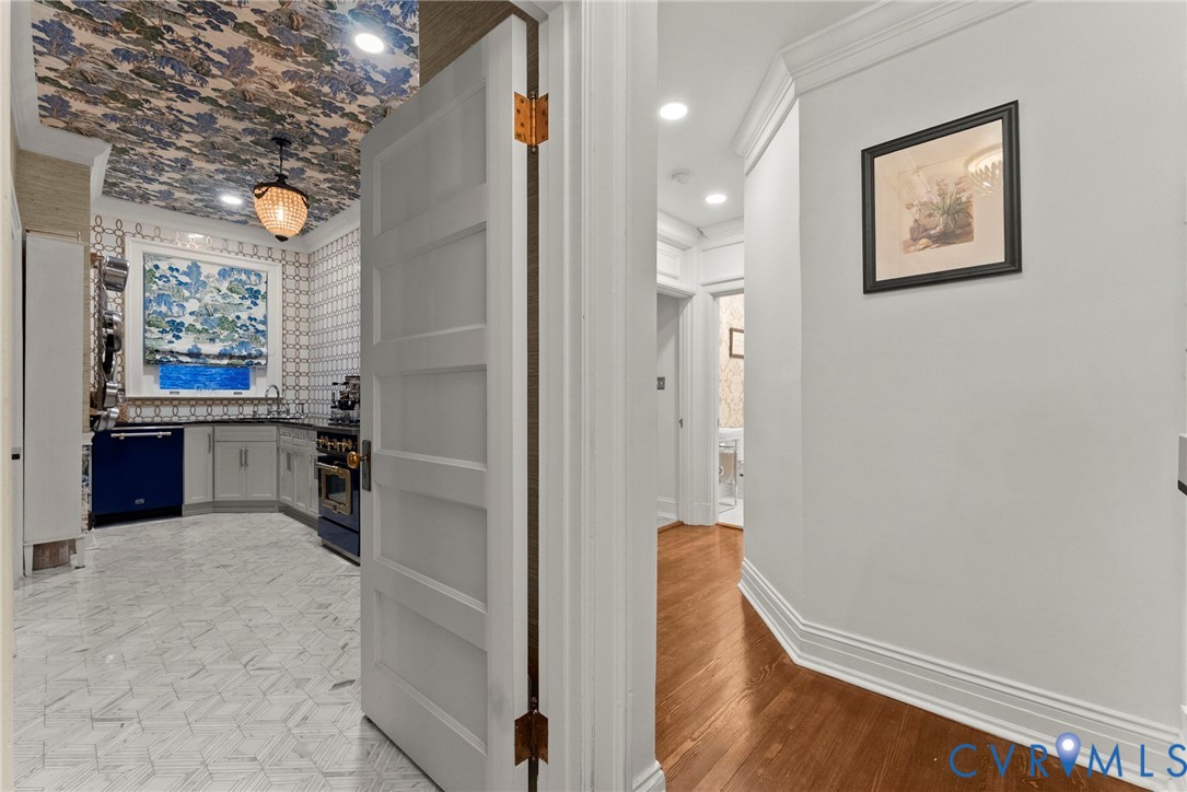 Kitchen featuring patterned ceiling wallpaper, geometric floor tile, built-in cabinetry, and recessed lighting, with hardwood flooring in the foyer