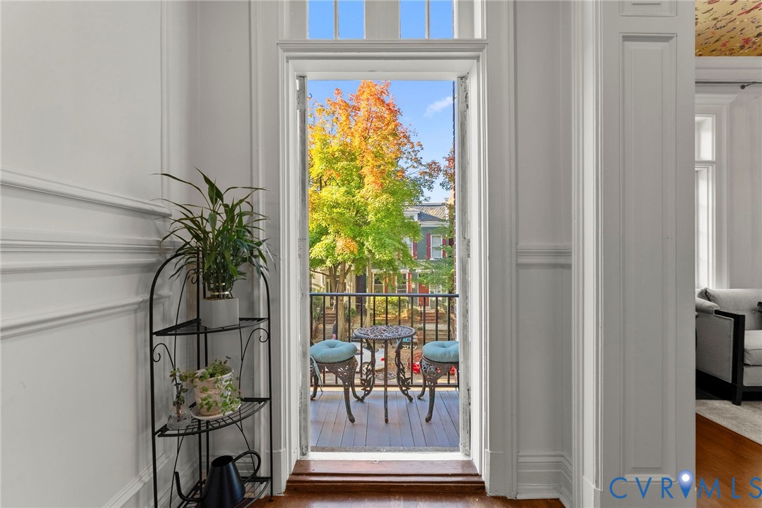 French door with glass transom light, interior millwork, and balcony featuring a metal railing