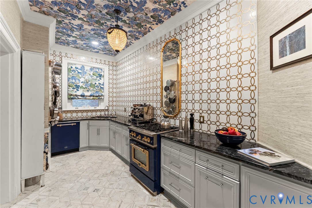 Kitchen featuring patterned wall tile, custom cabinetry, dark stone countertops, natural stone geometric floor tile, and integrated appliance suite