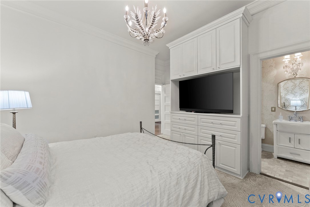 Built-in floor-to-ceiling cabinetry with integrated storage and media niche, multi-arm crystal chandelier, and crown molding