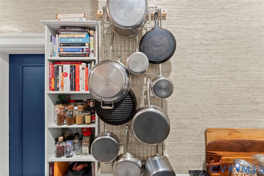 Built-in floor-to-ceiling white shelving unit featuring adjustable storage partitions and wall-mounted metal rack system for hanging cookware