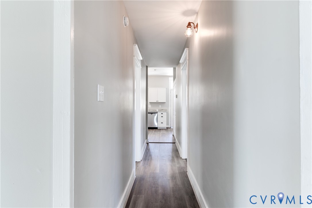 Interior hallway featuring wood-finish flooring, neutral wall tones, and a wall-mounted light fixture