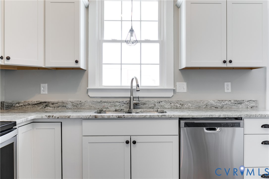 Kitchen featuring white shaker-style cabinetry, stone-patterned countertops, stainless steel undermount sink, brushed nickel high-arch faucet, and stainless steel dishwasher