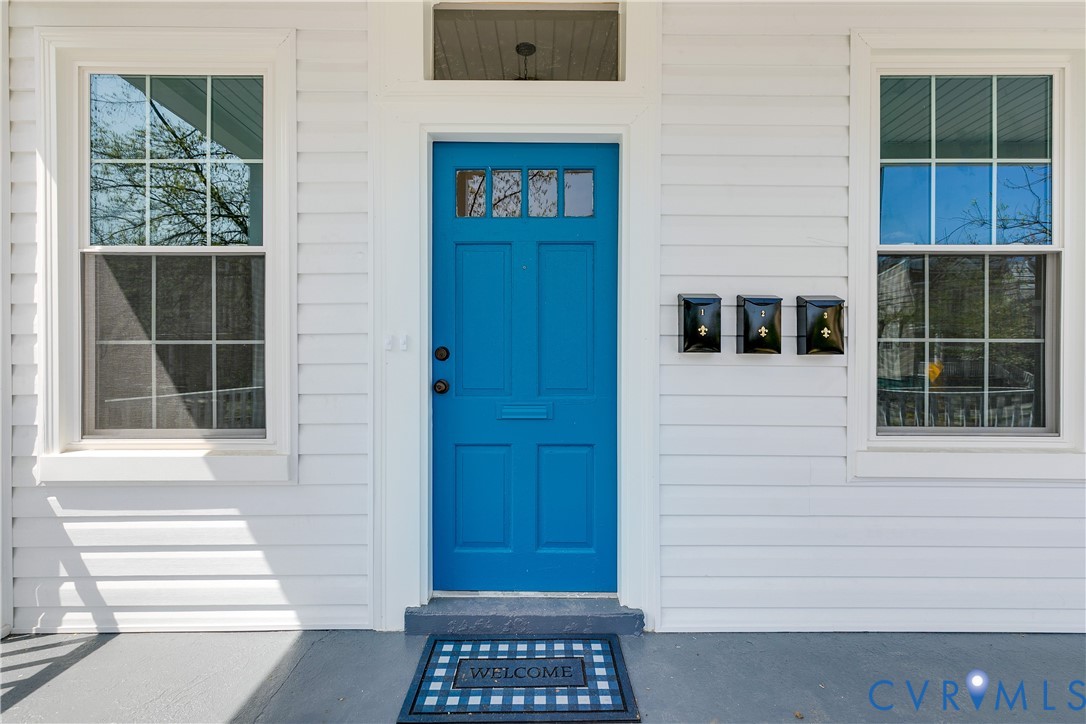 Exterior entrance featuring horizontal lap siding, a vibrant blue entry door with a multi-pane transom window, and symmetrical multi-pane windows