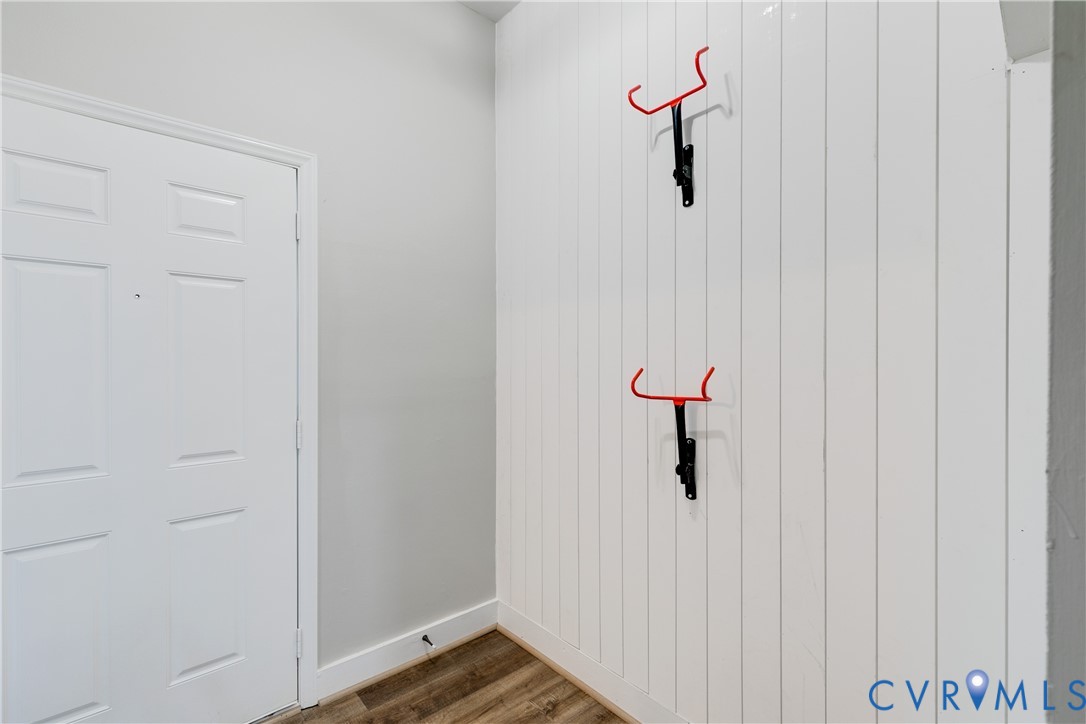 Interior space featuring wood-finish flooring, vertical shiplap wall paneling, and two wall-mounted metal hooks