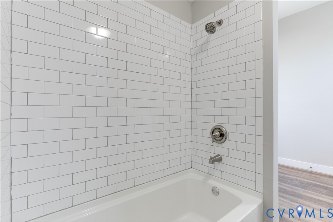 Full-height white subway tile surround, integrated soaking tub, and brushed nickel shower fixtures