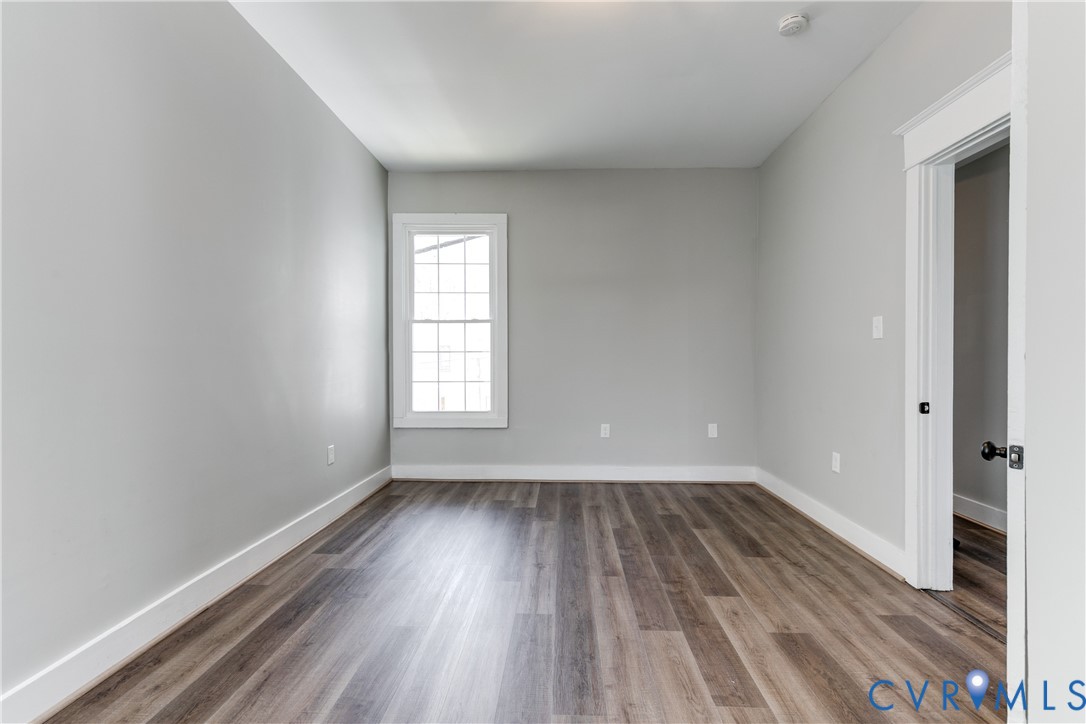 Neutral-toned interior featuring wood-finish flooring, white door casing, and a multi-pane window