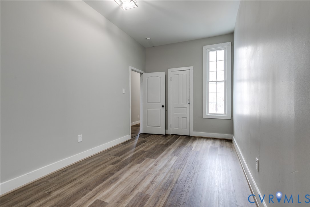 Interior space featuring wood-finish flooring, a tall multi-pane window, and two paneled interior doors