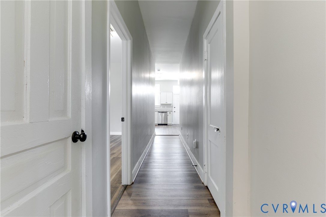 Hallway featuring wood-finish flooring, white five-panel interior doors, and matte black hardware