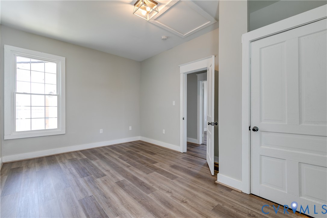 Neutral-toned room featuring wood-finish flooring, a multi-pane window, flush-mount light fixture, and a two-panel interior door