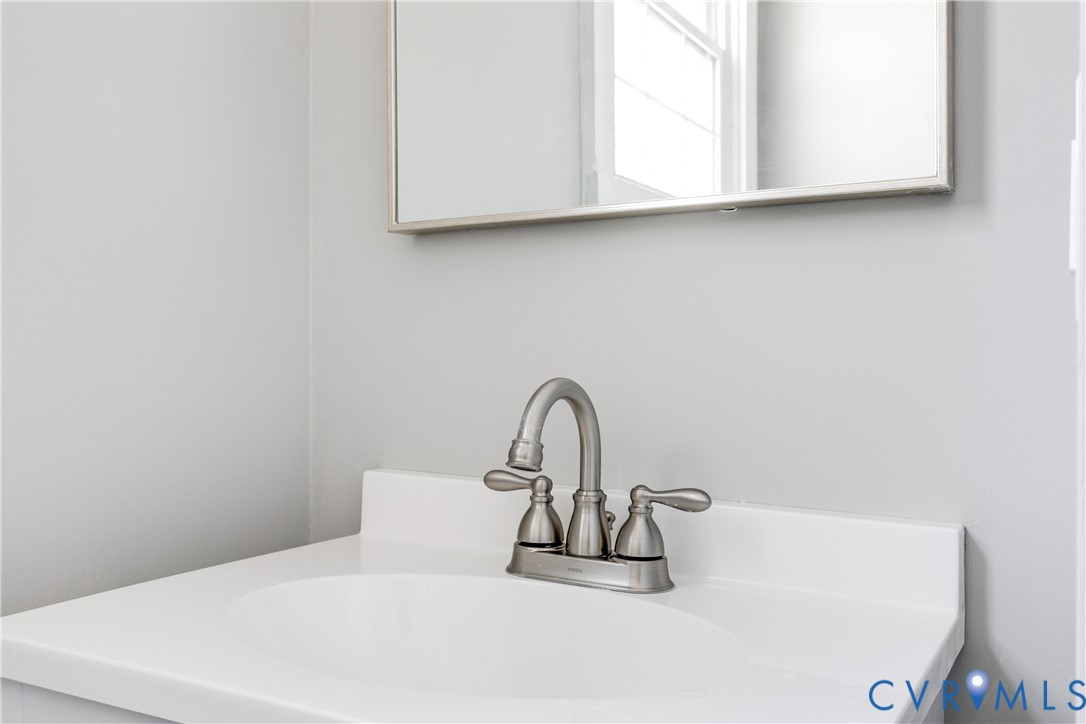 White countertop with an integrated basin, paired with a brushed nickel double-handle faucet and a rectangular framed mirror
