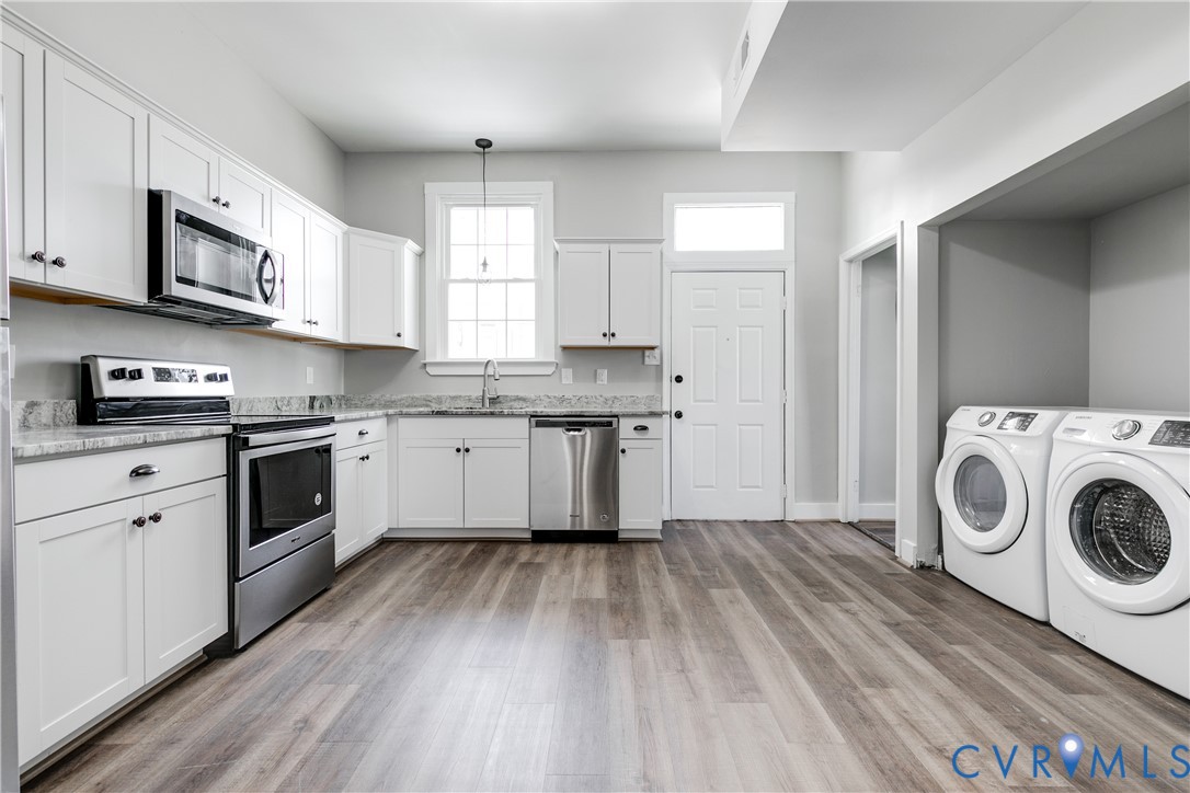 Kitchen featuring white shaker-style cabinetry, stone countertops, stainless steel appliances, and wood-finish flooring