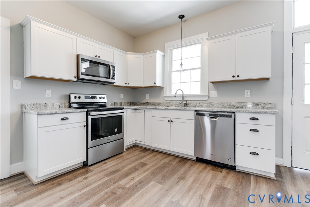 Kitchen featuring white cabinetry, stone-finish countertops, stainless steel appliances, and wood-finish flooring