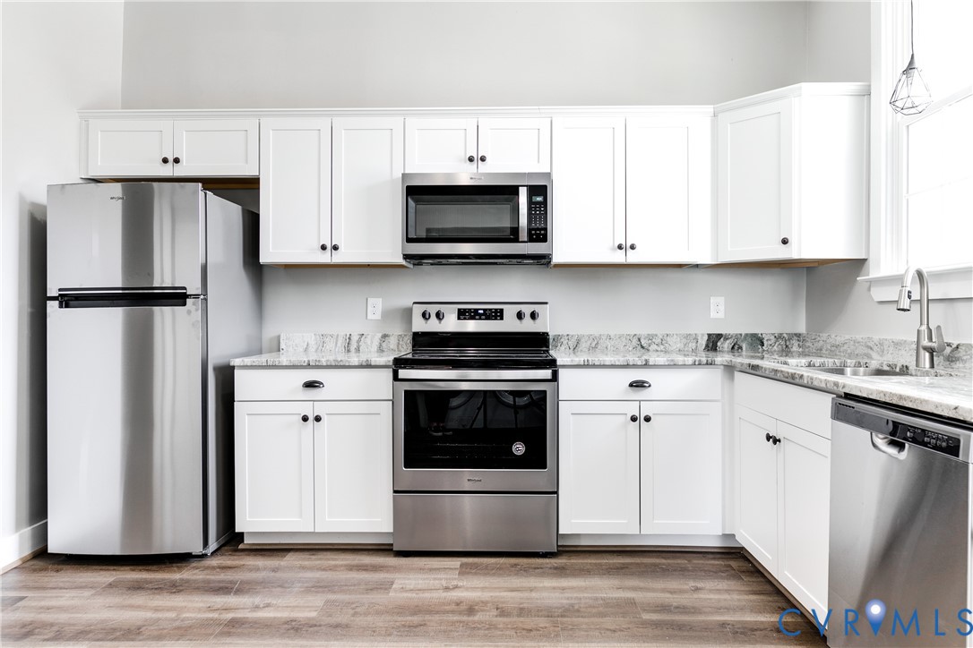Kitchen featuring white cabinetry, stone-finish countertops, stainless steel appliances, and wood-finish flooring