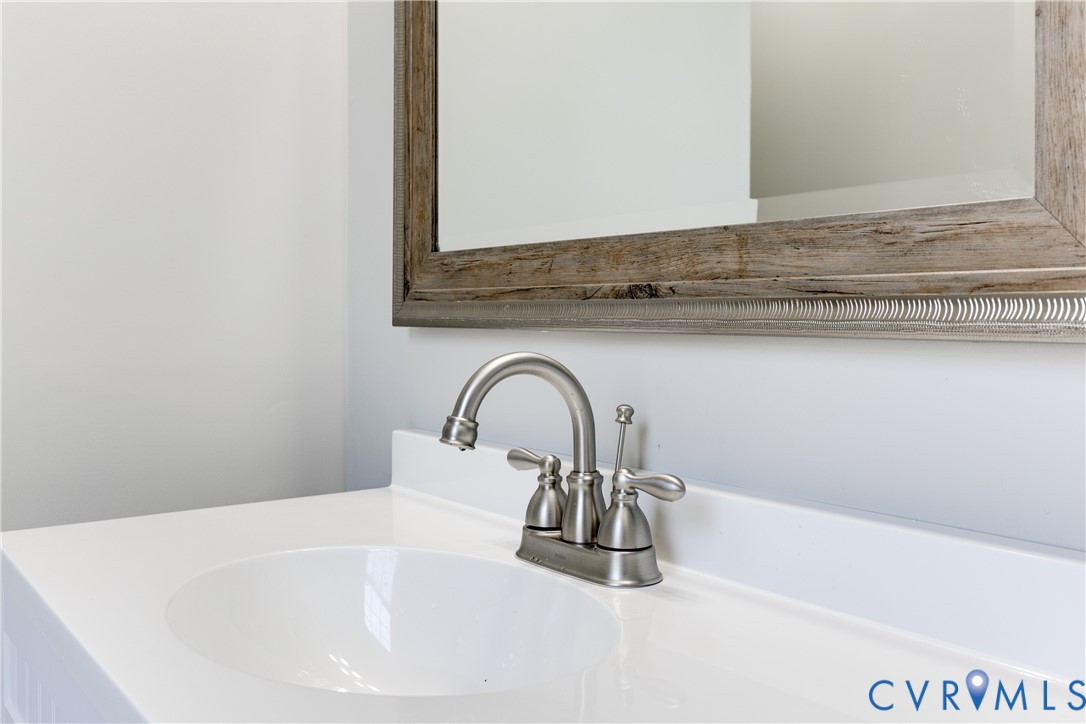 Integrated vanity featuring a solid-surface countertop, an oval undermount sink, a dual-handle brushed nickel faucet, and a decorative wood-finish framed wall mirror