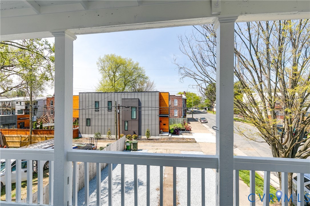 Covered porch featuring white wood railings and structural columns