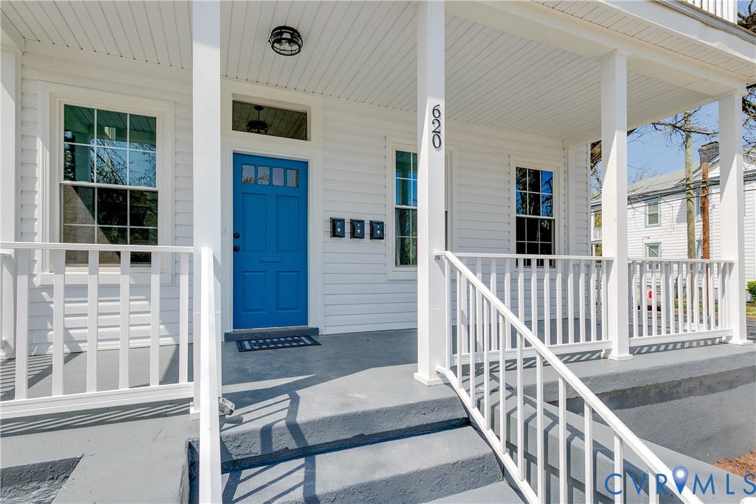 Covered front porch featuring white lap siding, square support columns, a white railing system, and a blue paneled front door with a transom window