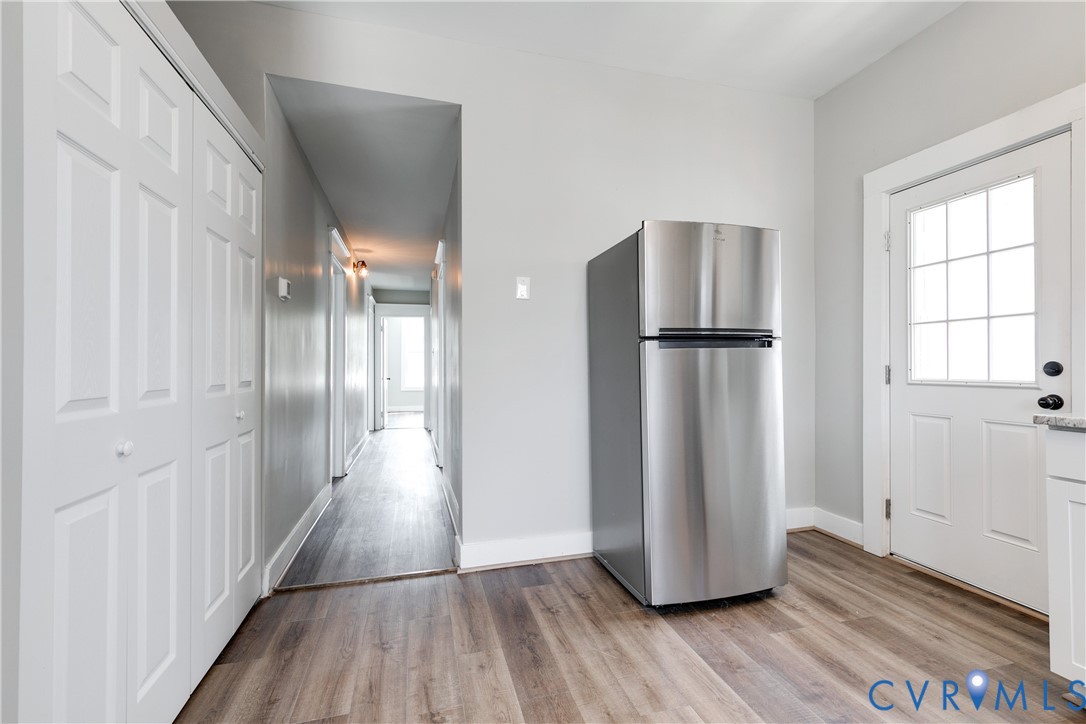 Stainless steel refrigerator, wood-finish flooring, white paneled closet doors, and a six-lite glass-paneled exterior door