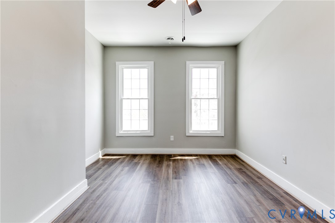 Neutral-toned interior featuring wood-finish flooring, dual grid-pattern windows, and a ceiling-mounted light fixture