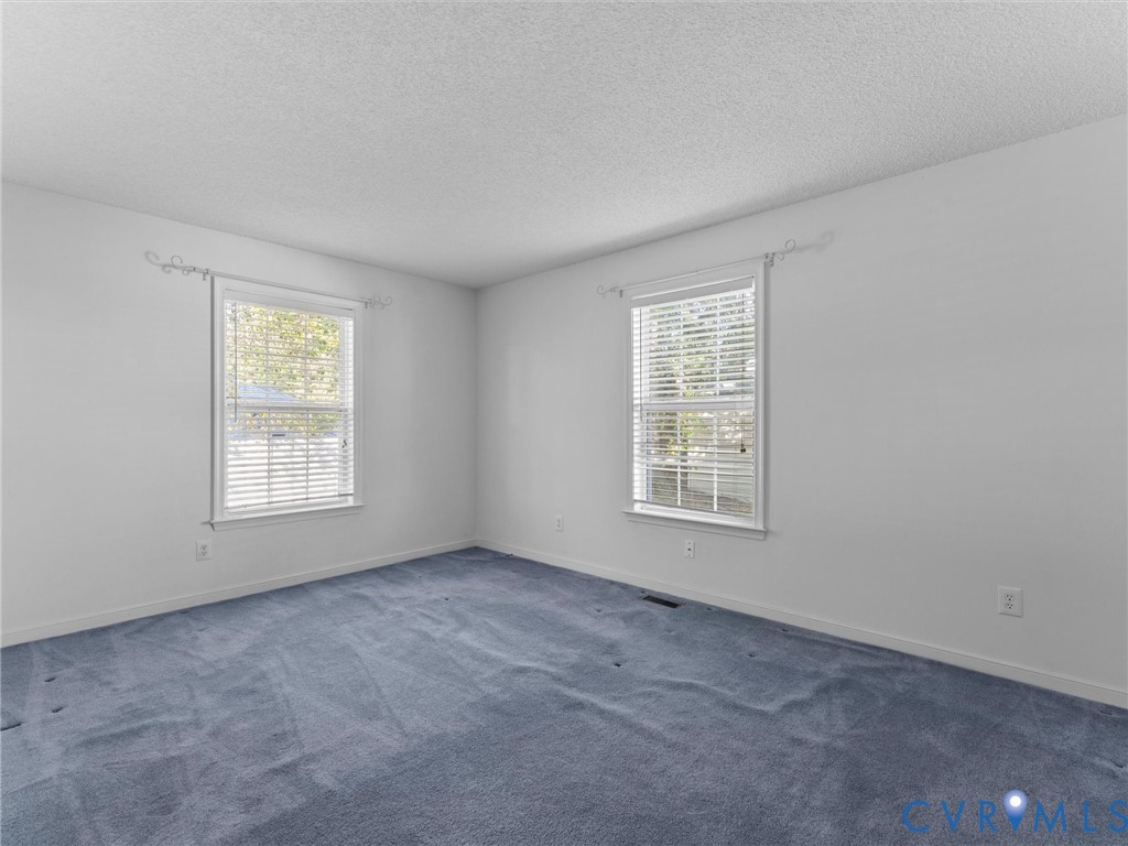 Neutral interior featuring wall-to-wall carpeting, white walls, and dual double-hung windows with white frames and blinds