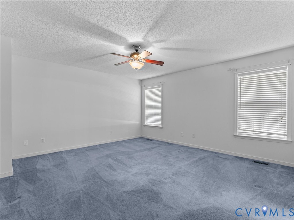 Room featuring wall-to-wall carpeting, dual windows with fitted blinds, and a central ceiling fan with integrated lighting