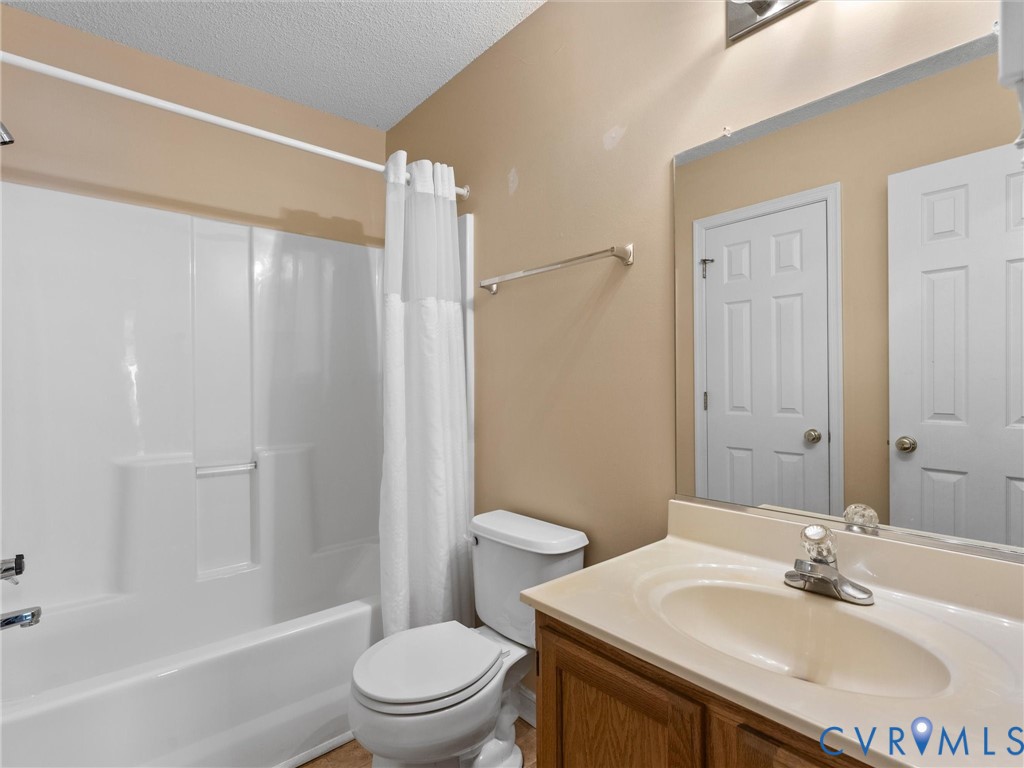 Bathroom featuring a molded composite tub and shower surround, wood-finish vanity with an integrated basin, wall-mounted mirror, and six-panel interior doors