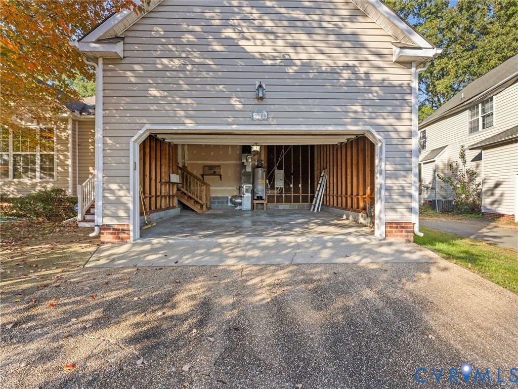 Detached garage with horizontal vinyl siding, brick foundation accents, and an open bay configuration