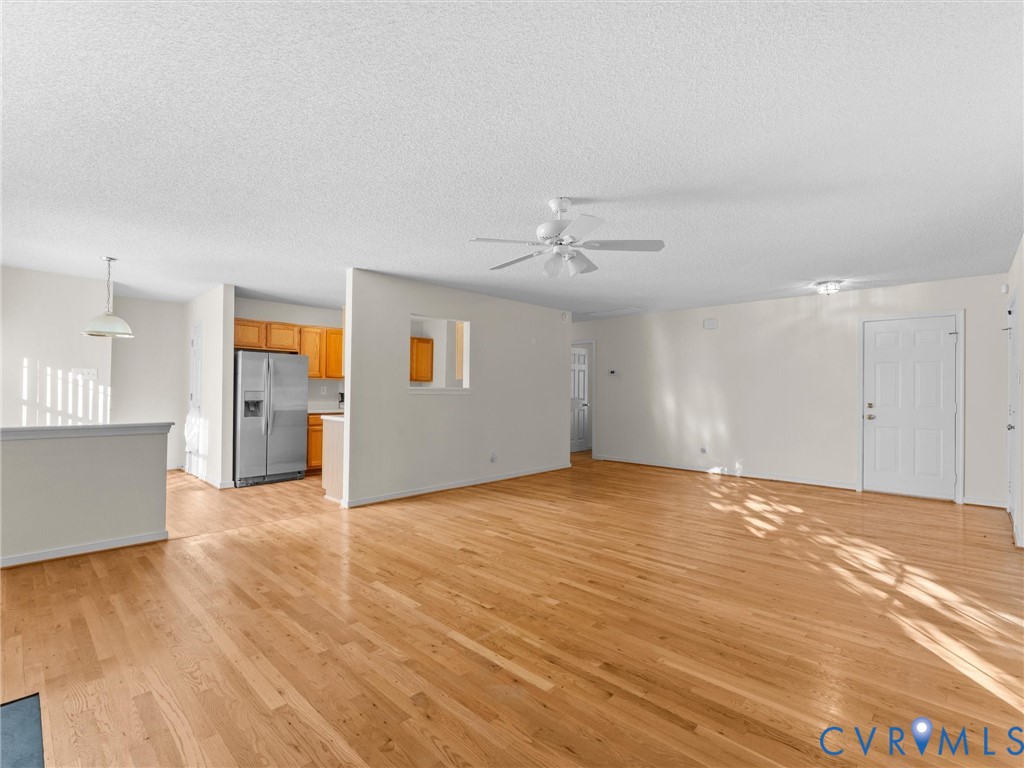 Open-concept interior featuring wood-finish flooring, a pass-through wall cutout, a ceiling fan, and built-in cabinetry