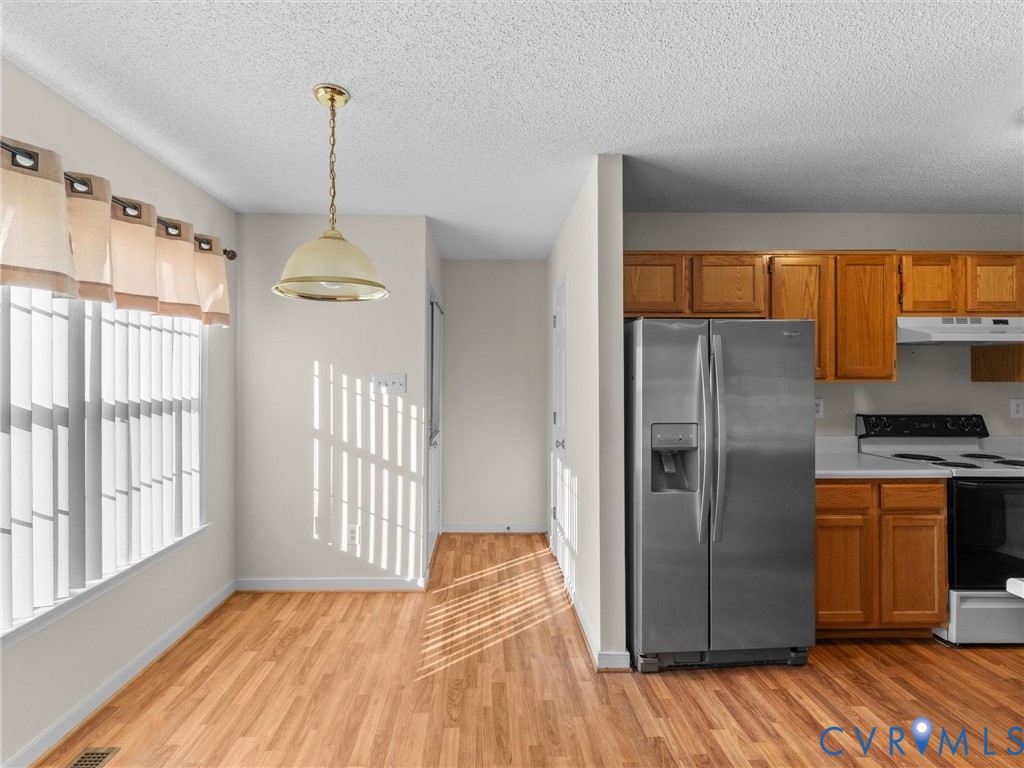 Kitchen featuring natural wood cabinetry, stainless steel side-by-side refrigerator, white range, and wood-finish flooring with a dome pendant light fixture