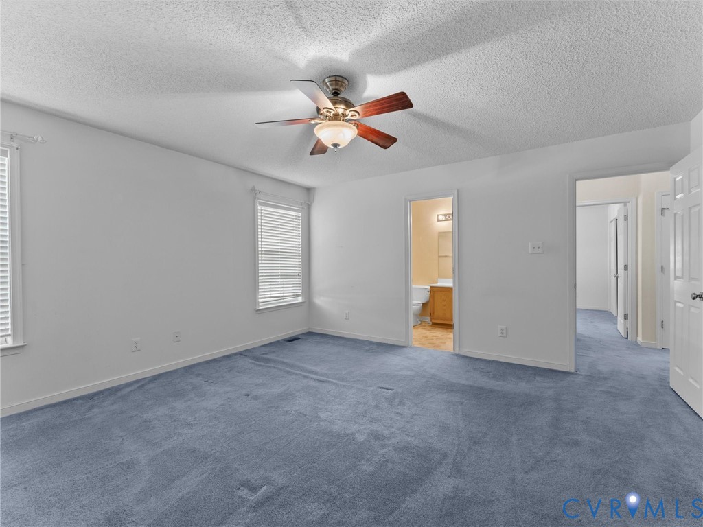 Room featuring wall-to-wall carpeting, a ceiling fan with integrated lighting, dual windows with horizontal blinds, and a multi-panel interior door