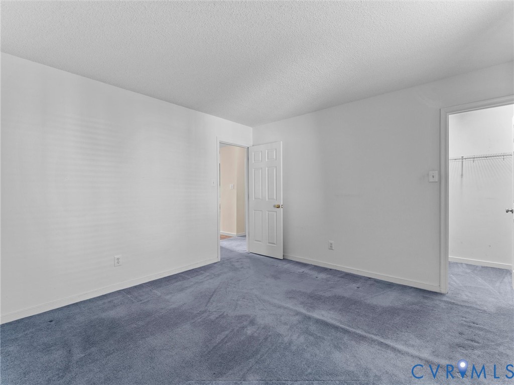 Room featuring wall-to-wall carpeting, white textured ceiling, and a six-panel interior door
