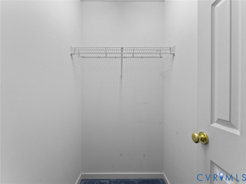 Storage area featuring white paneled door with brass hardware and wire shelving