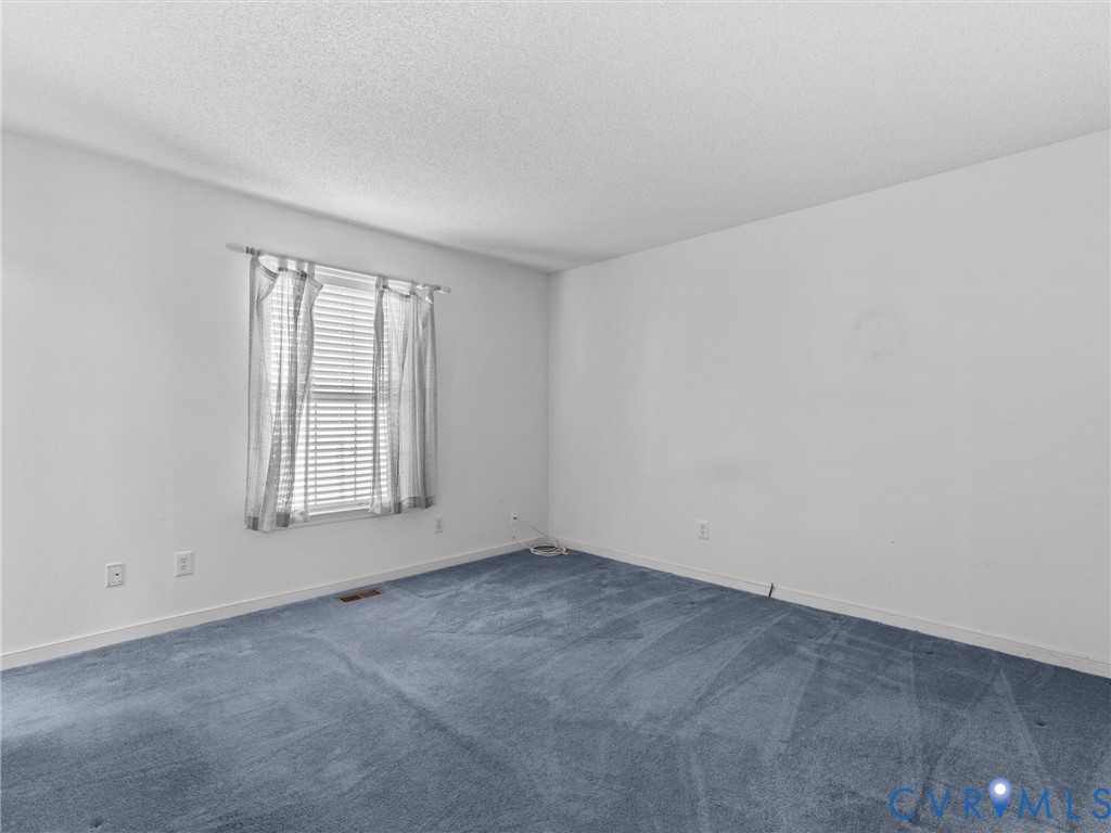 Neutral-toned interior space featuring blue carpeting, a single-pane window, and white walls